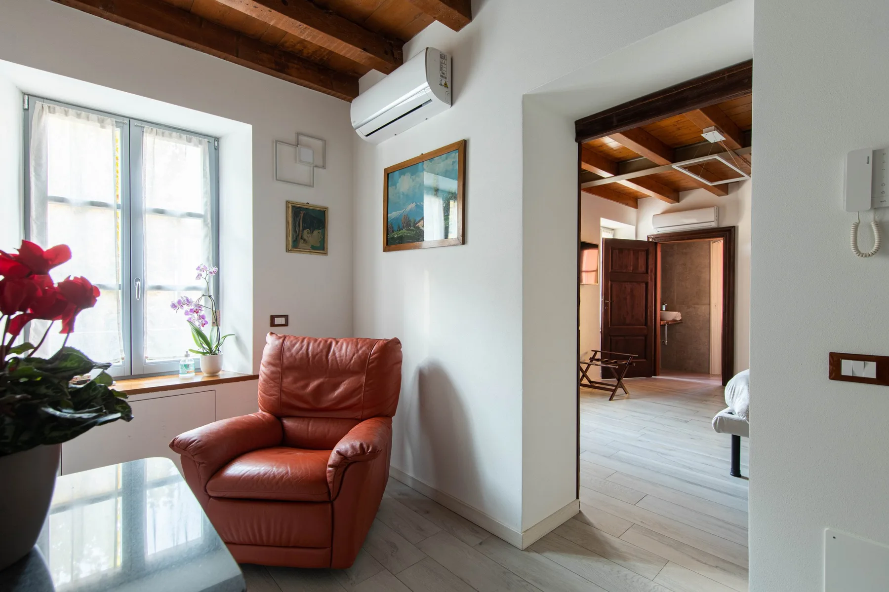 Una luminosa zona de estar tiene un sillón rojo junto a una ventana grande.