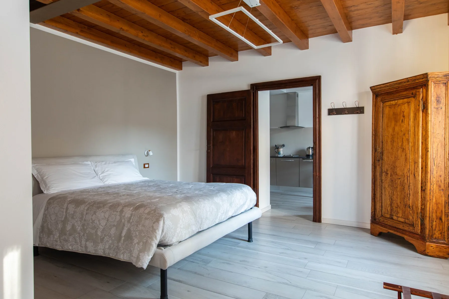 Un dormitorio con una cama, vigas de madera en el techo y un armario grande.