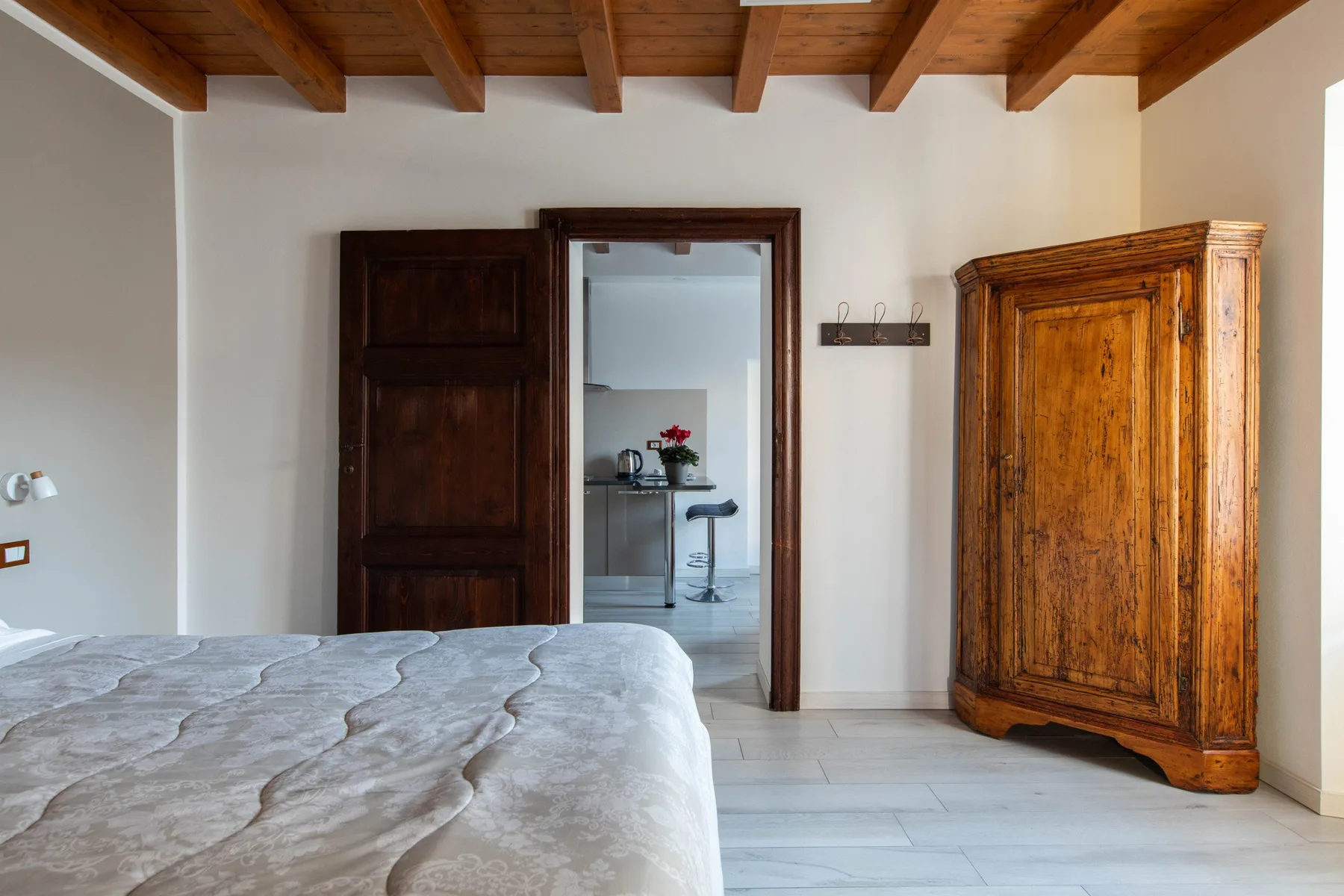 Un dormitorio con una cama, un armario de madera y una puerta abierta a una pequeña cocina.