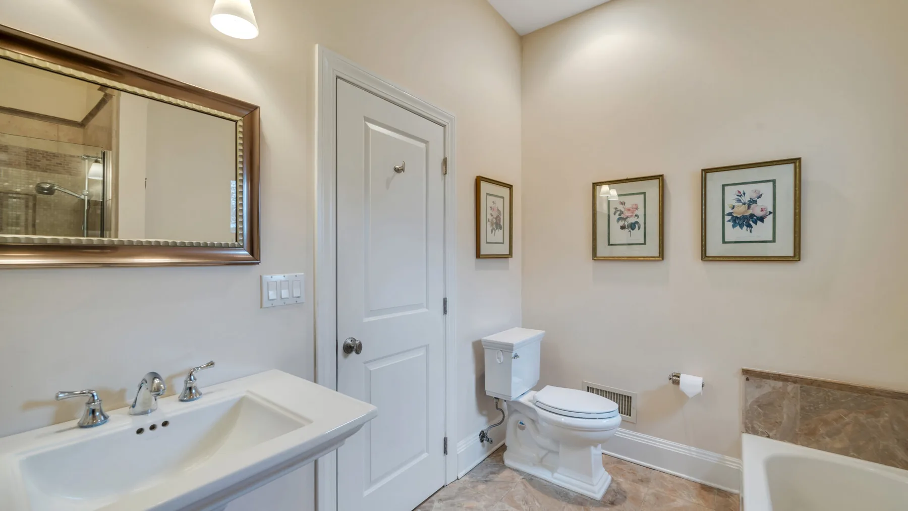 Un baño con lavabo, inodoro y cuadros en la pared.