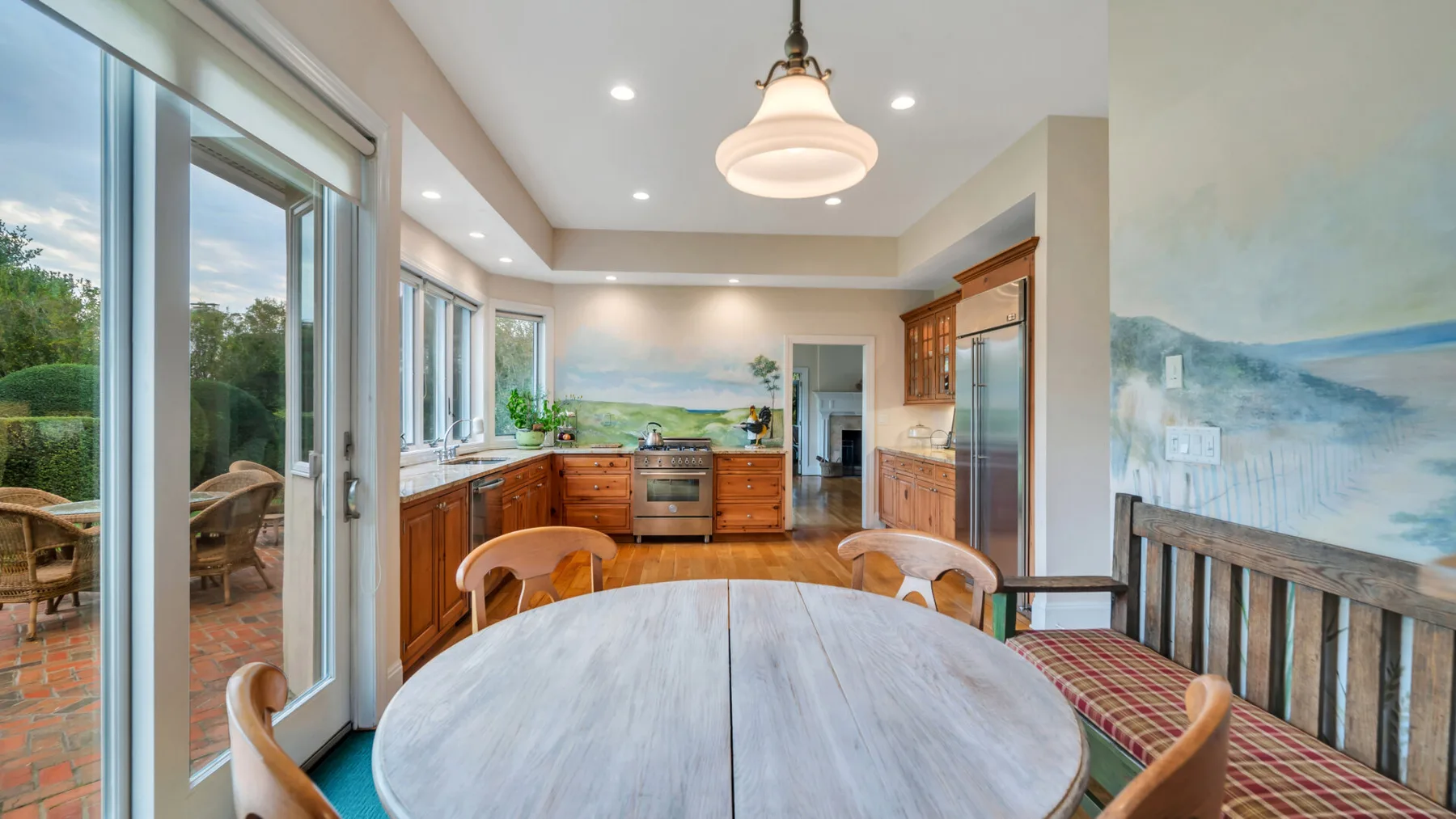 Una cocina luminosa con comedor, mesa redonda y grandes ventanas.