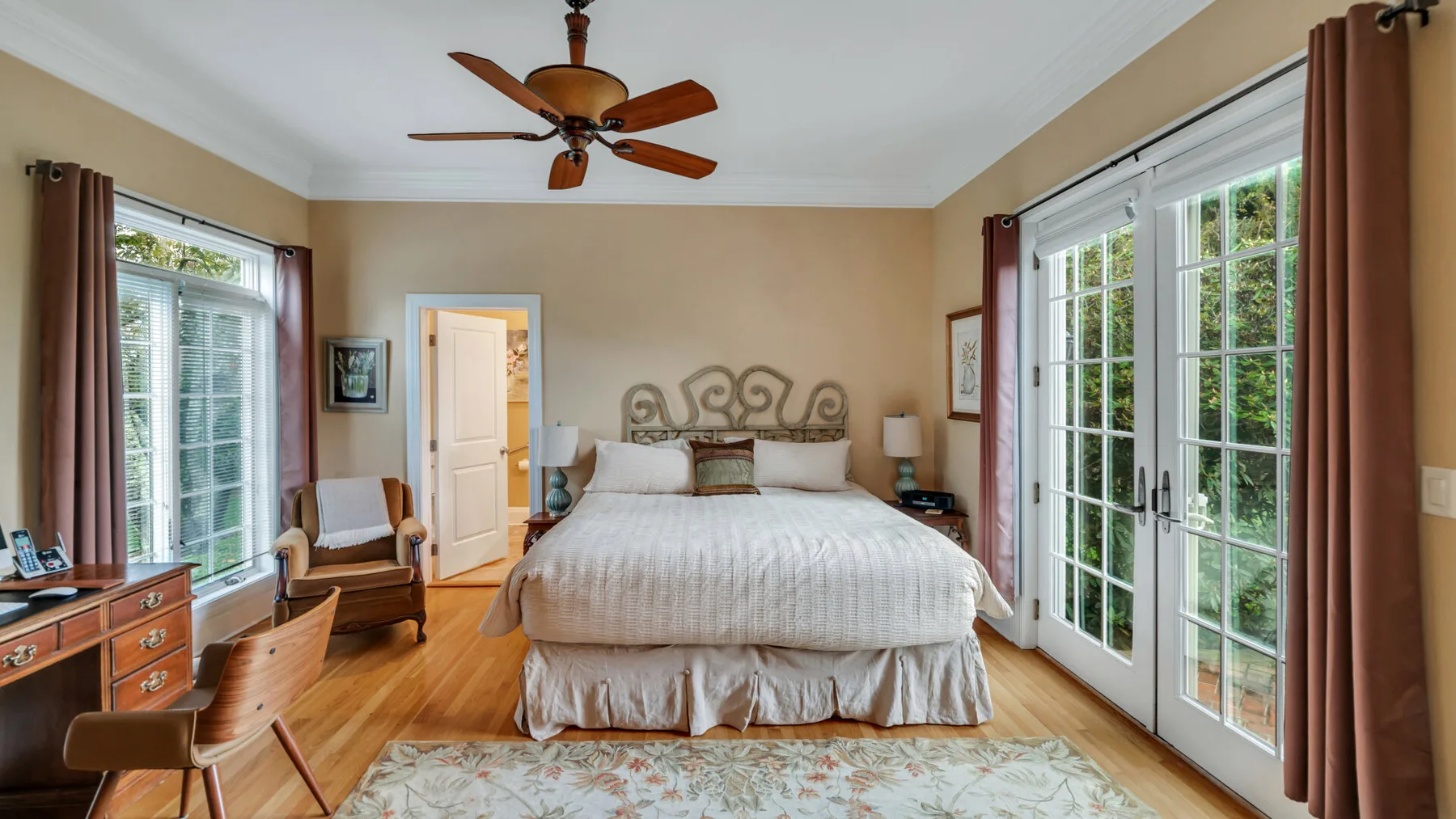 Dormitorio con una cama entre ventanas y puertas de vidrio.