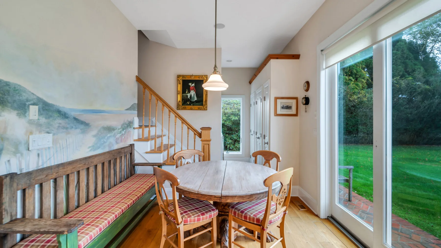 Comedor con mesa de madera y asientos junto a grandes puertas de vidrio.