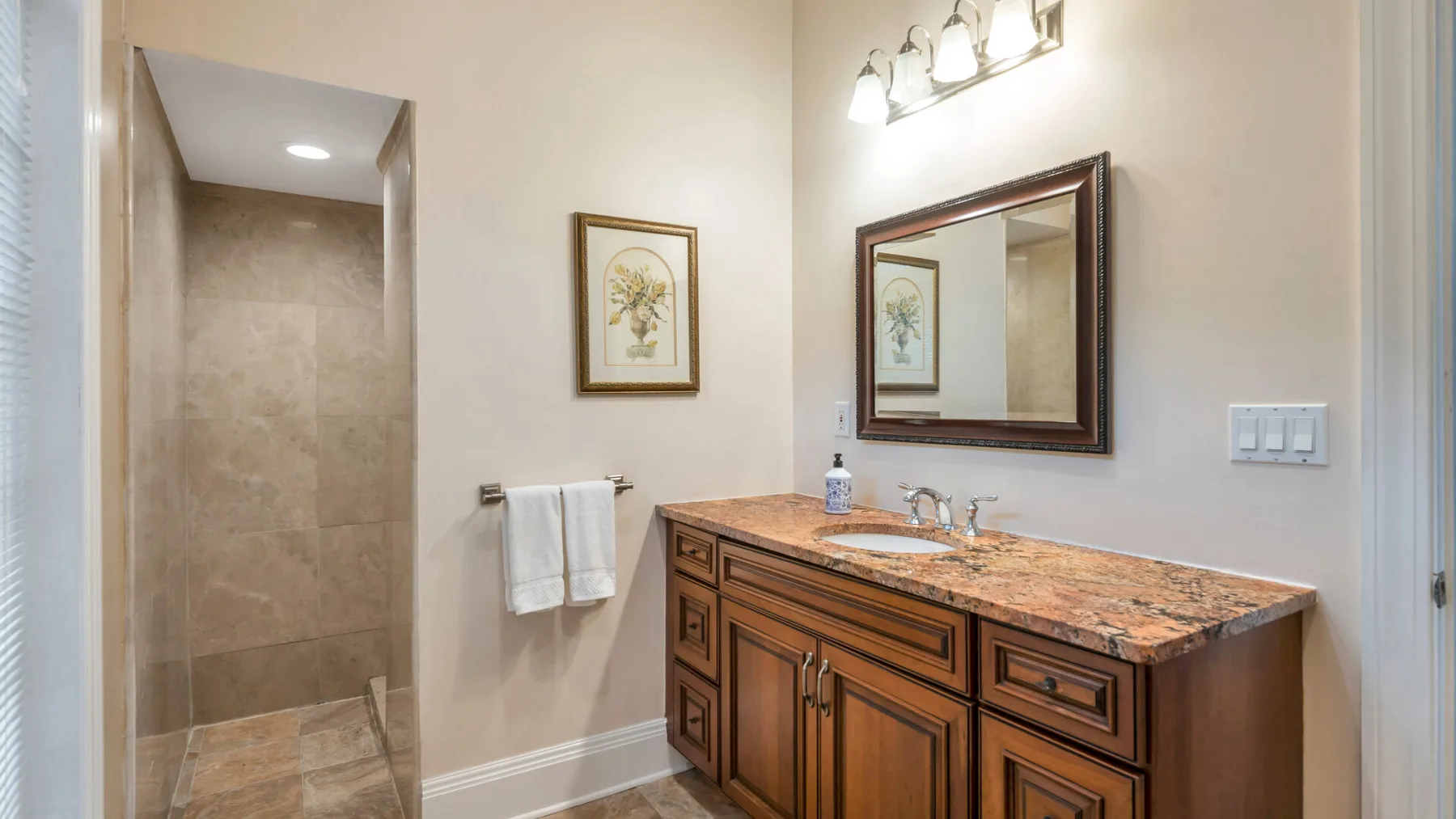 Un tocador de baño con espejo y una zona de ducha con azulejos.
