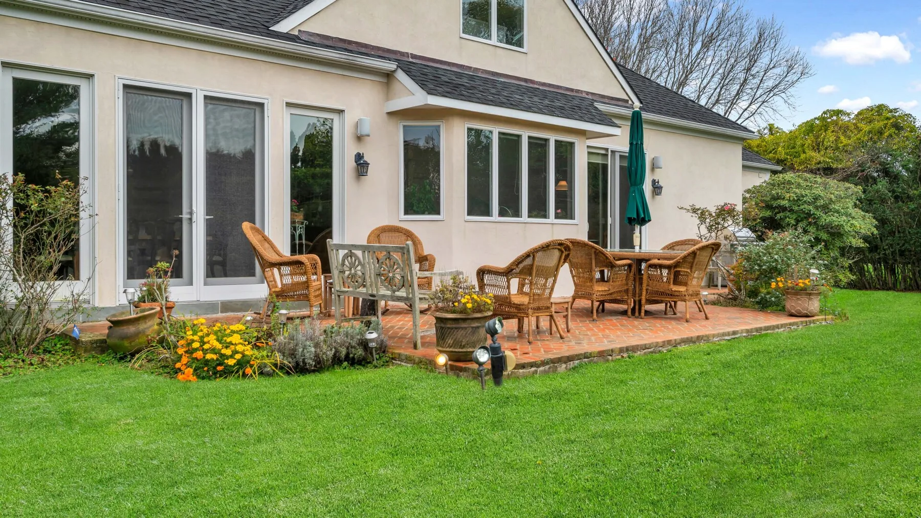 Un patio con asientos al aire libre y césped verde junto a una casa.