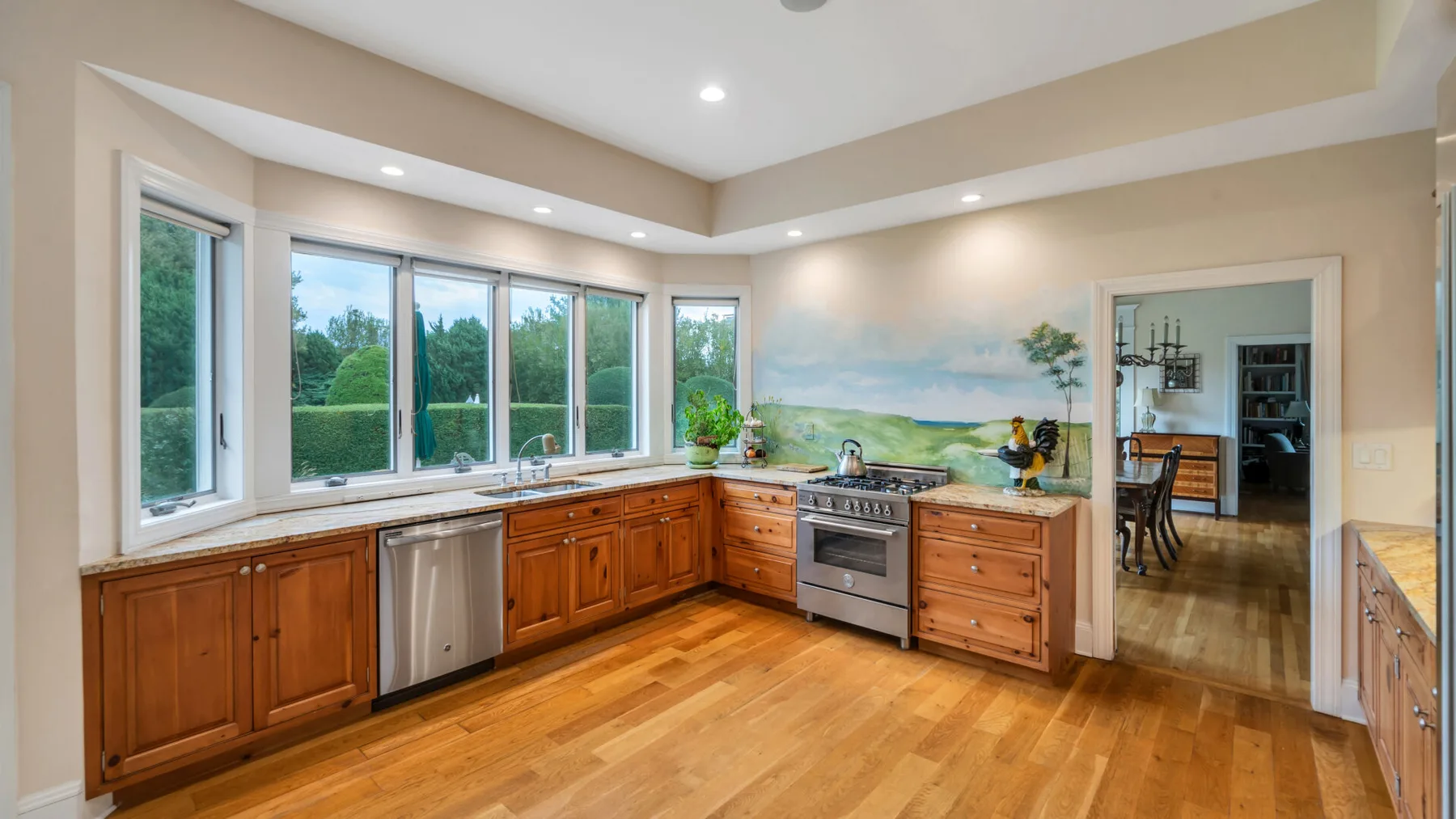 Una cocina amplia con gabinetes de madera, ventanas grandes y una zona de cocción central.