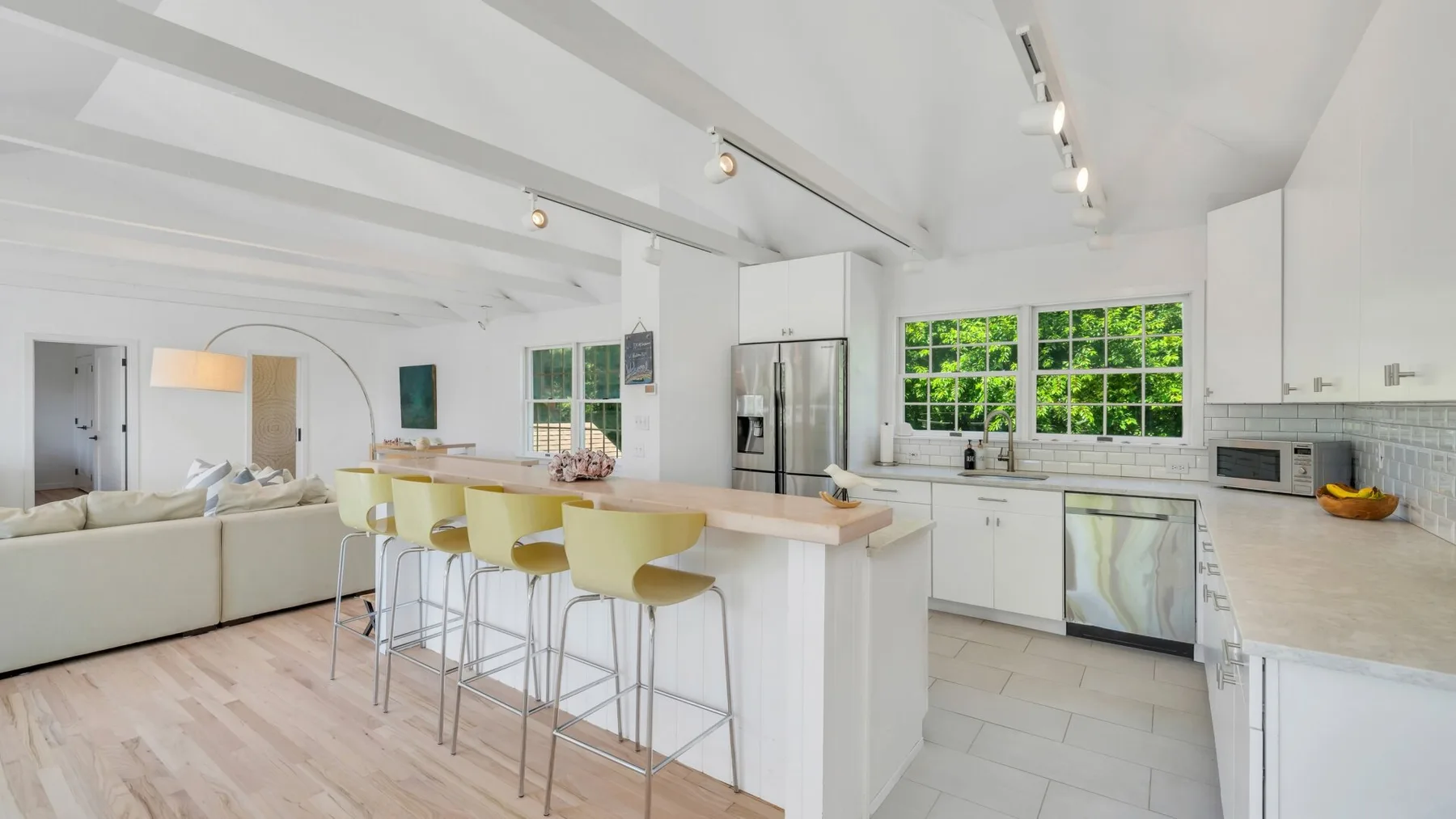 Una luminosa cocina abierta al salón, con una isla central y ventanas grandes.