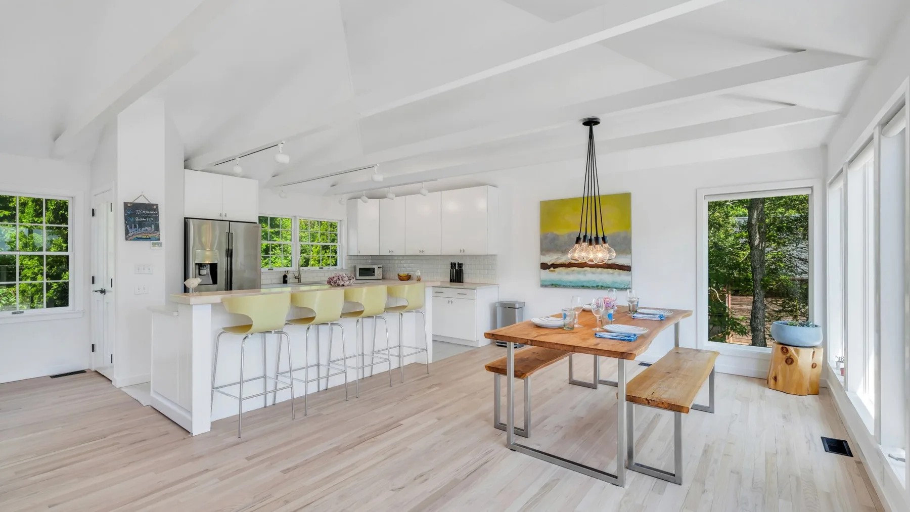 Una luminosa cocina-comedor de planta abierta con una isla larga y una mesa de madera.