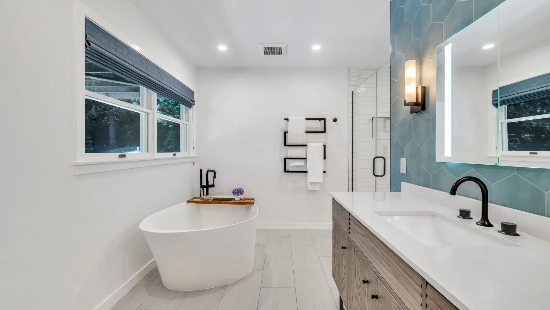 Un baño luminoso con bañera exenta, ducha de vidrio y un tocador largo.