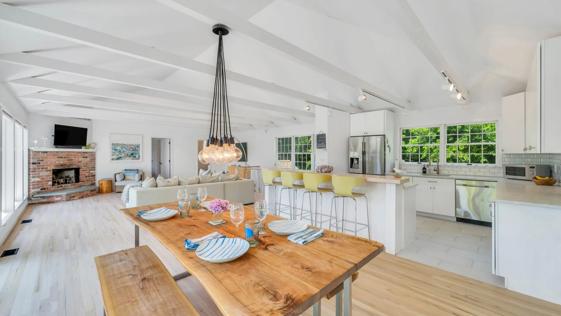Una sala de estar y cocina de concepto abierto con una mesa de comedor de madera.