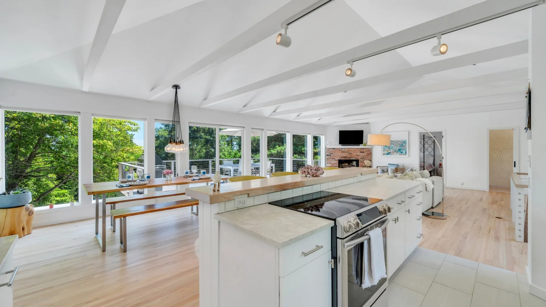Una cocina luminosa con una isla grande y ventanas con vistas a árboles frondosos.