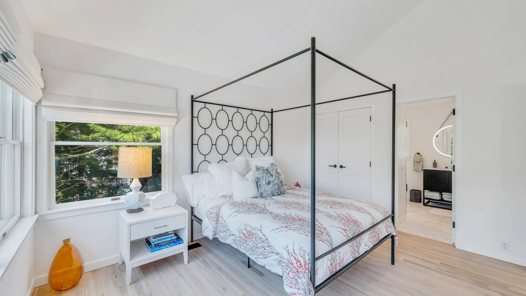 Un dormitorio luminoso con una cama con dosel junto a una ventana grande.