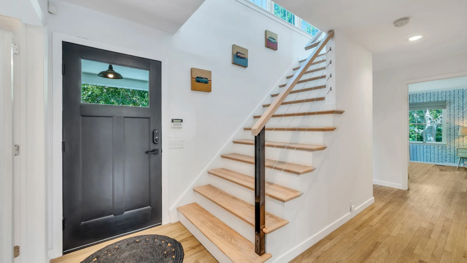 Una entrada con una puerta oscura y una escalera de madera.