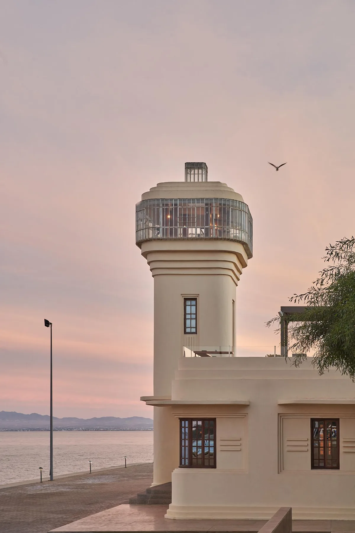 El faro del complejo junto al agua al atardecer.