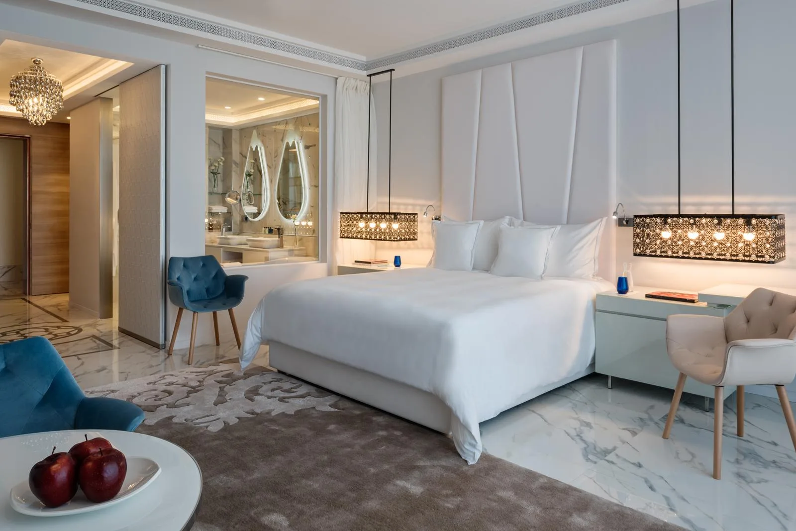 Habitación de hotel con una cama, sillones y vistas hacia el baño.
