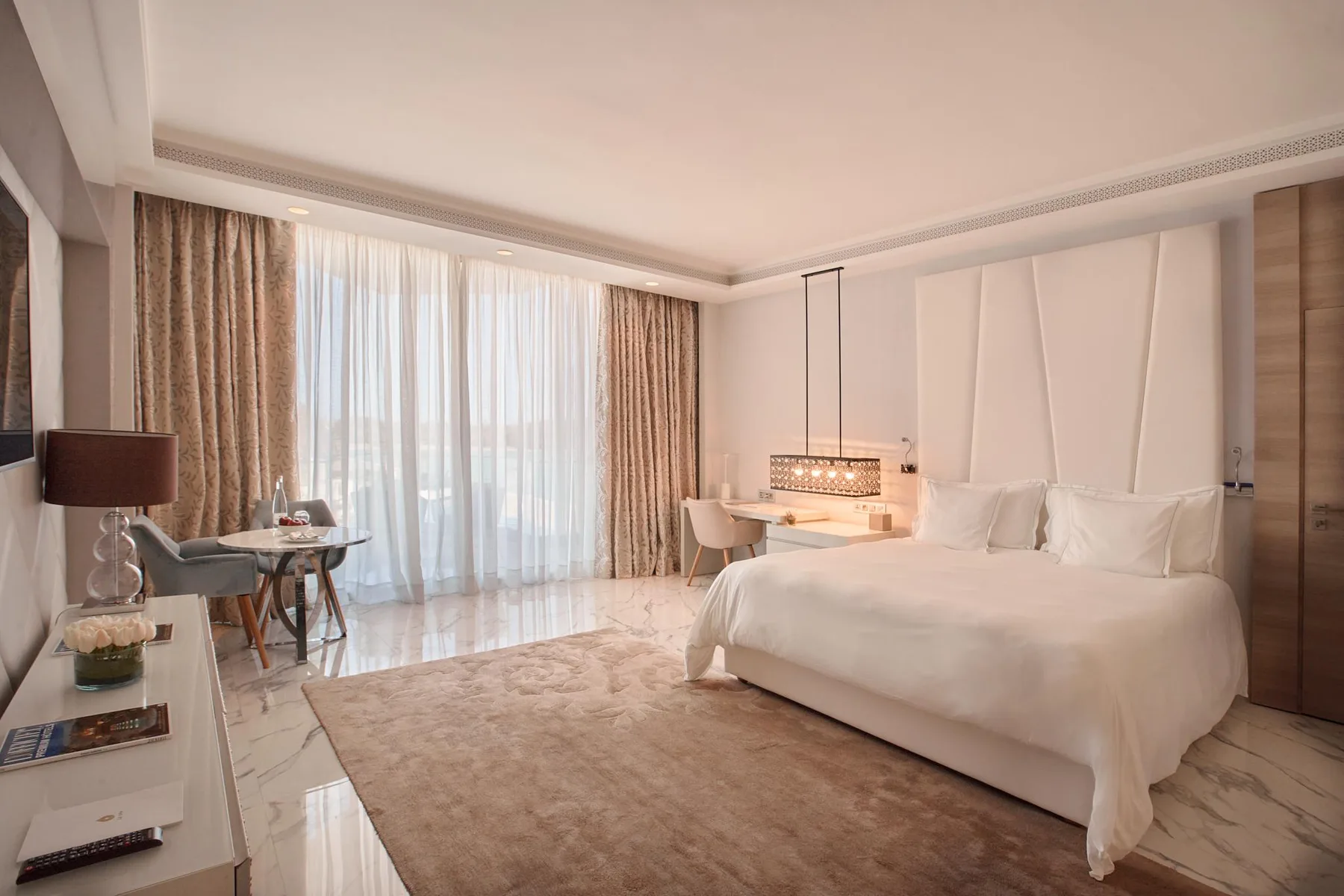 Habitación de hotel con una cama grande y una zona de estar junto a una ventana.
