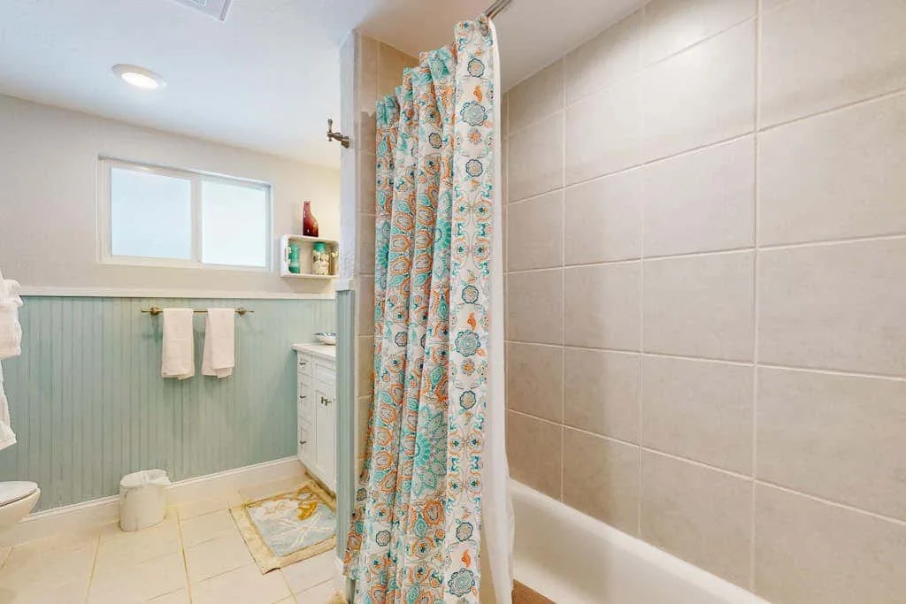 Un baño con bañera y cortina de ducha estampada junto a una ventana.