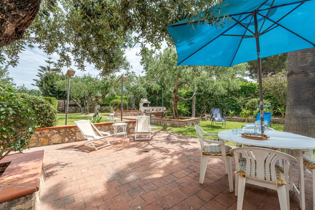 A garden patio with outdoor seating beneath a blue umbrella.