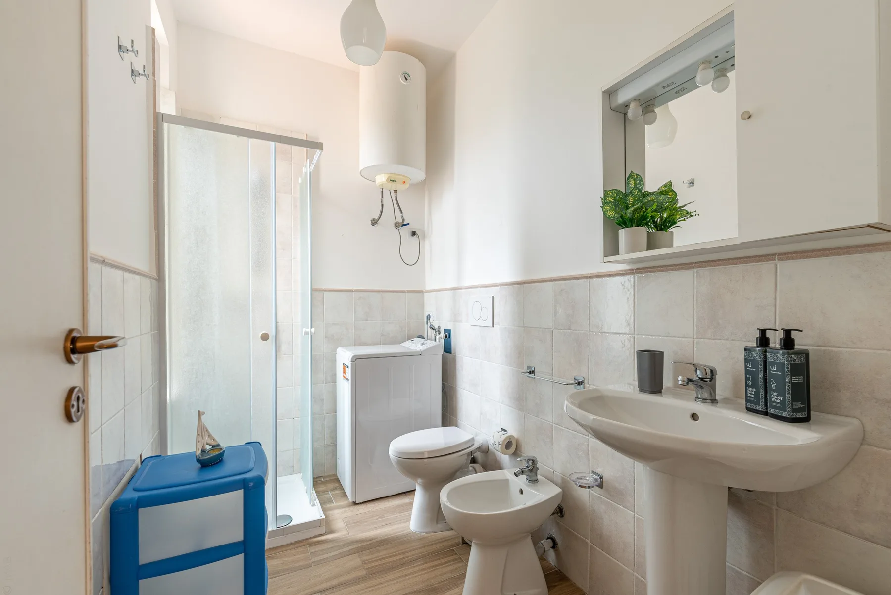 A tiled bathroom with a shower, toilet, bidet, and sink.