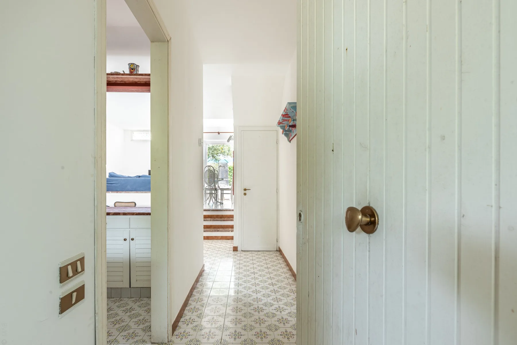 A tiled hallway leads toward a doorway beside a partially visible kitchen.