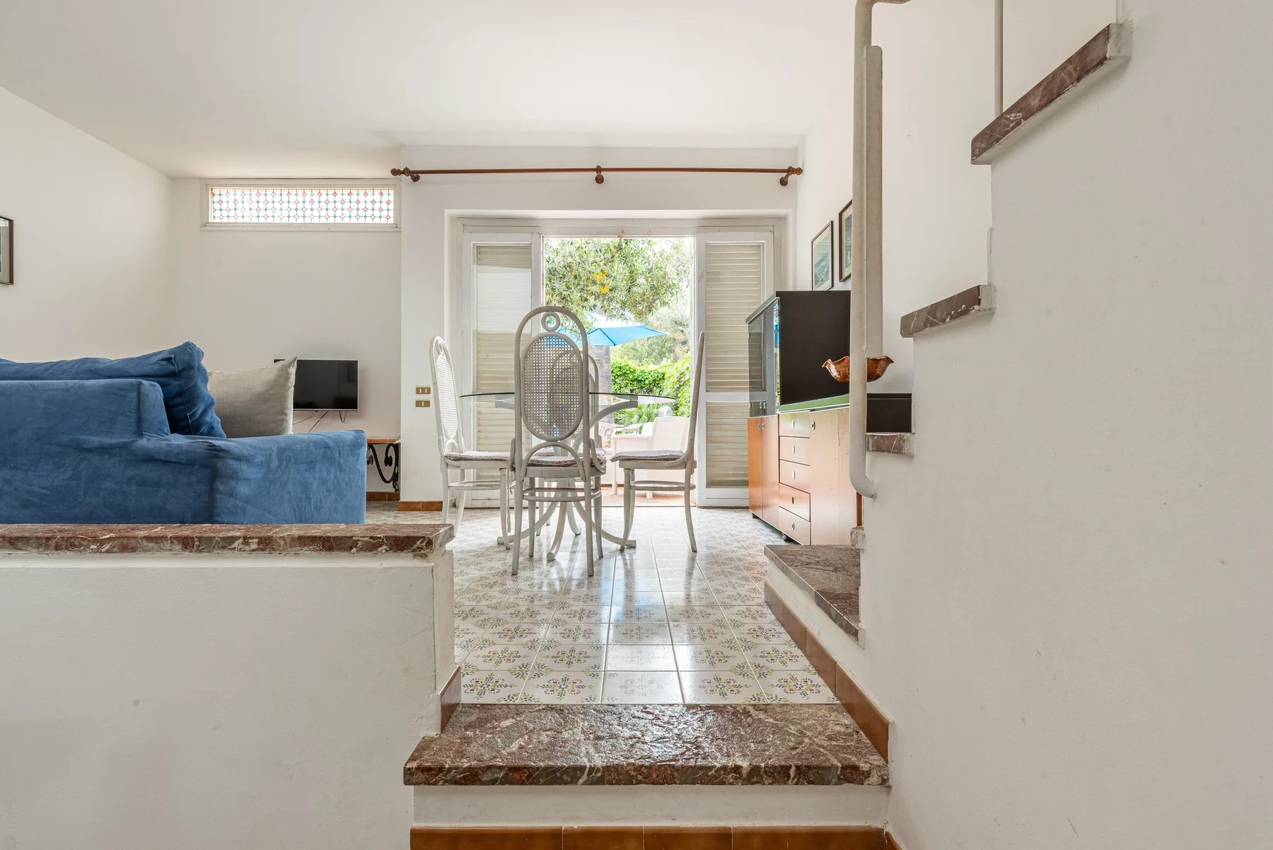 A bright living and dining area opens onto a balcony through glass doors.