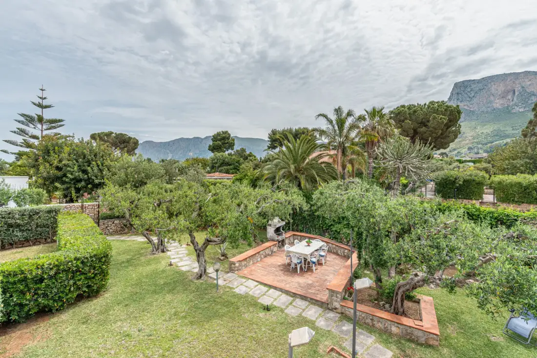 A landscaped garden with a paved patio and surrounding greenery.