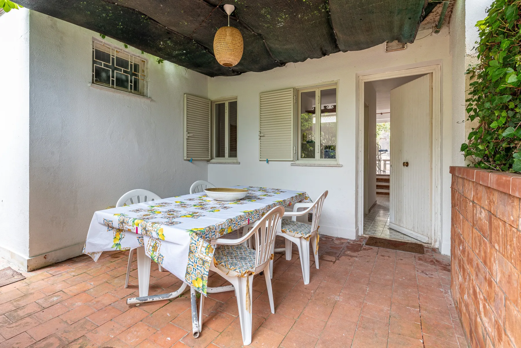 A covered patio dining area with a table and chairs.