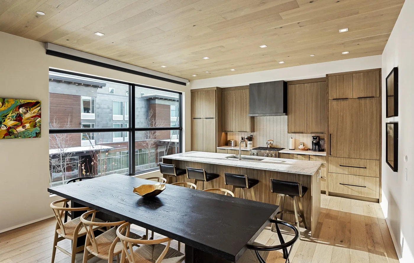 A modern kitchen and dining area with a long island and large windows.