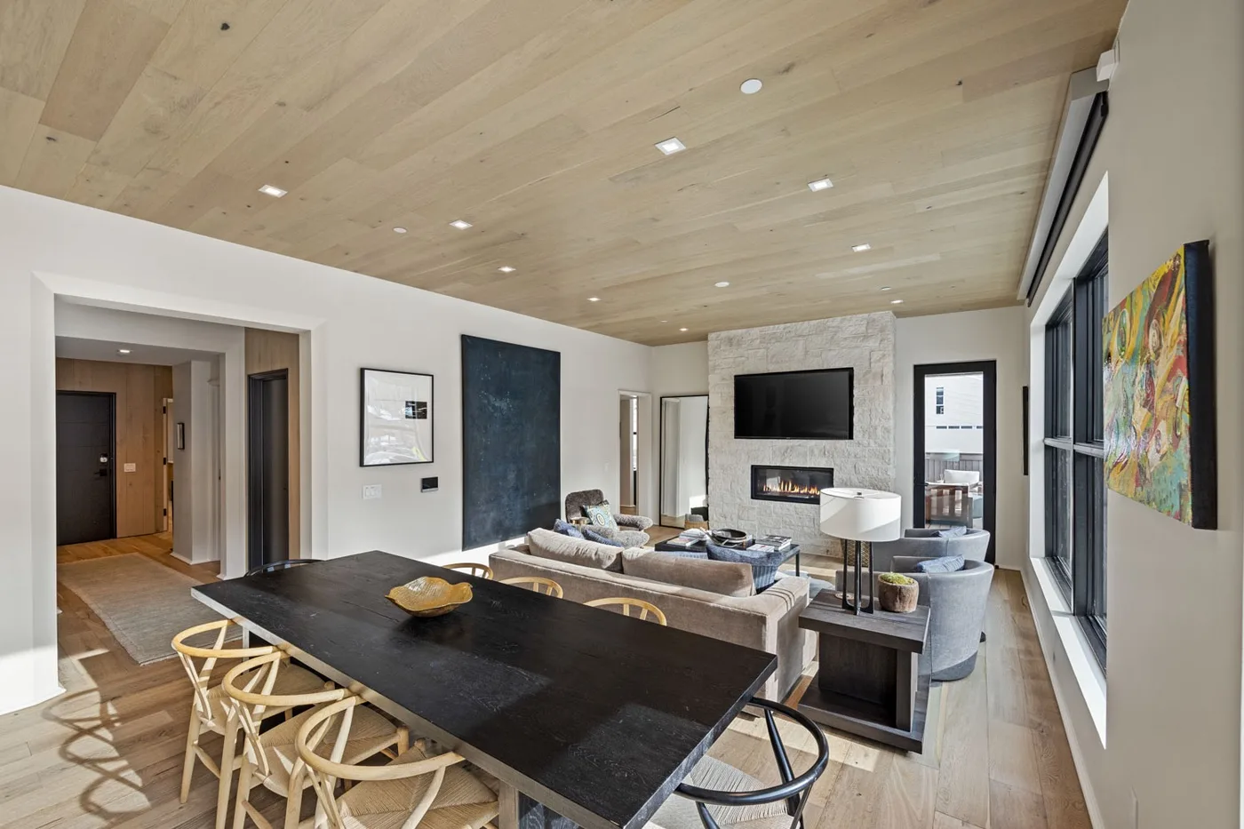 An open-plan living and dining area features a large table and seating around a fireplace.