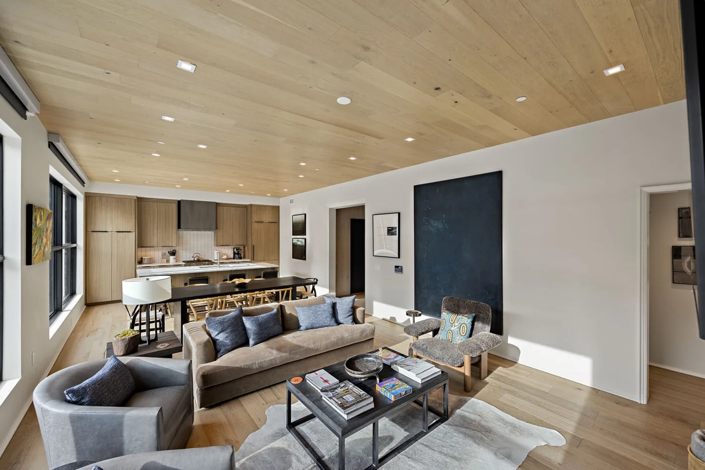 An open-plan living room with seating and a kitchen in the background.