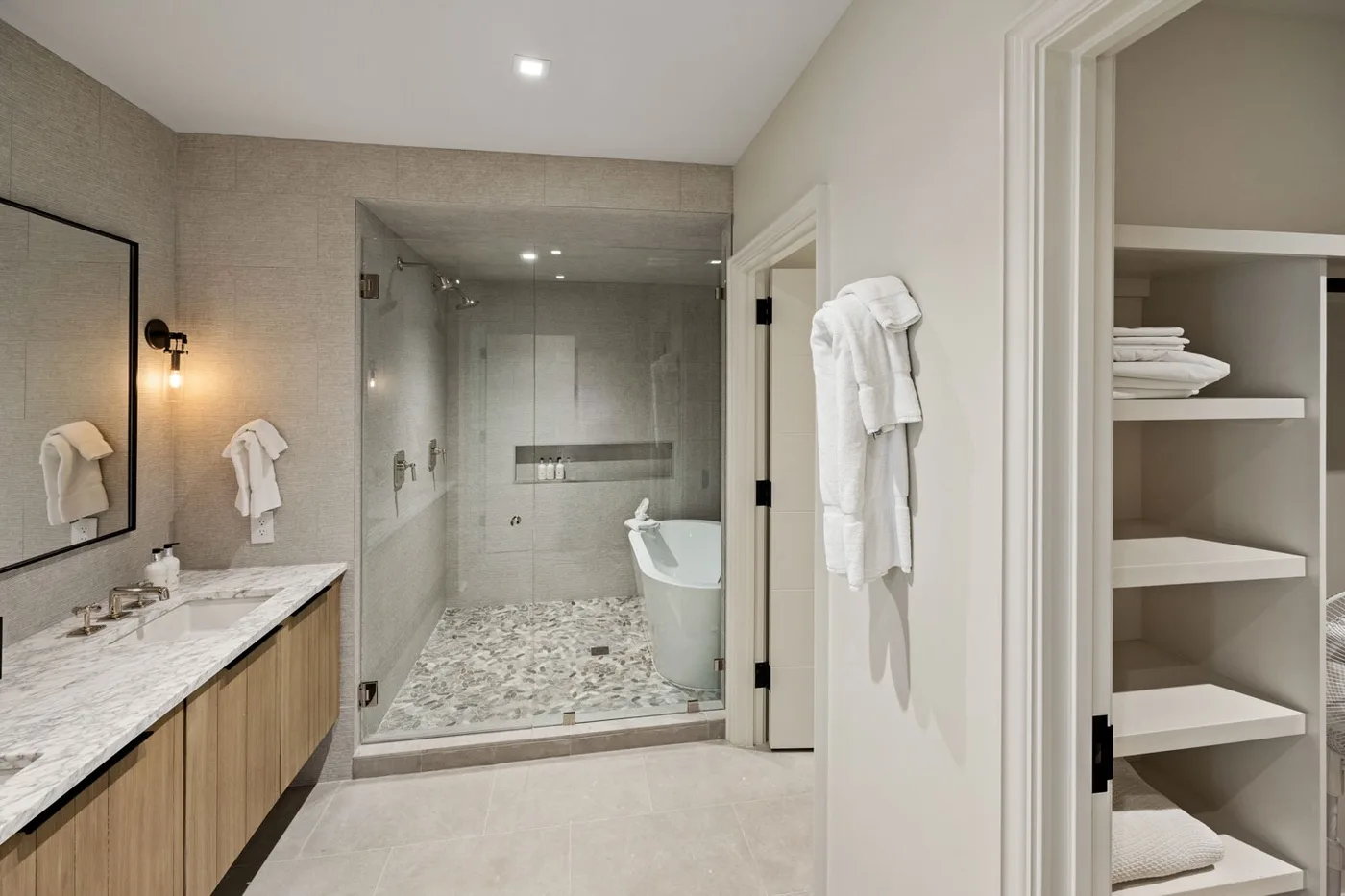 A bright bathroom with a glass shower and a vanity.