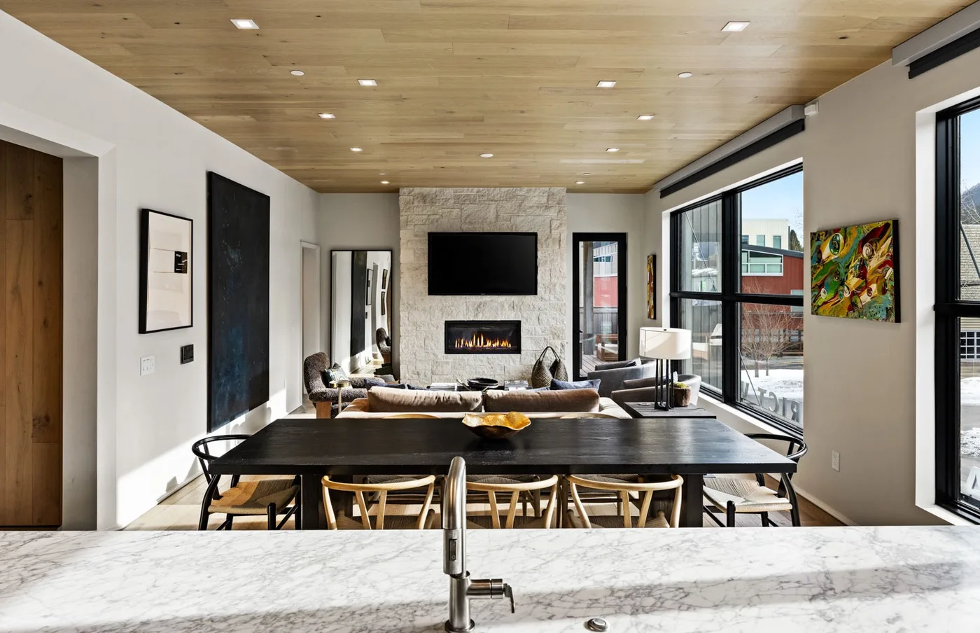 An open-plan living and dining area features a long table and a fireplace.