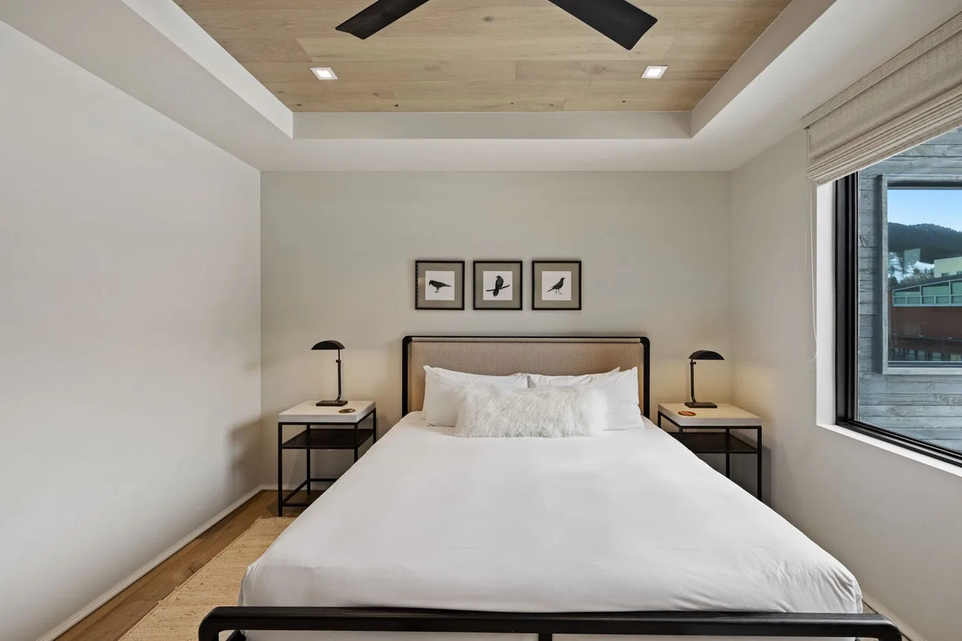 A bedroom with a neatly made bed, bedside tables, and framed artwork.
