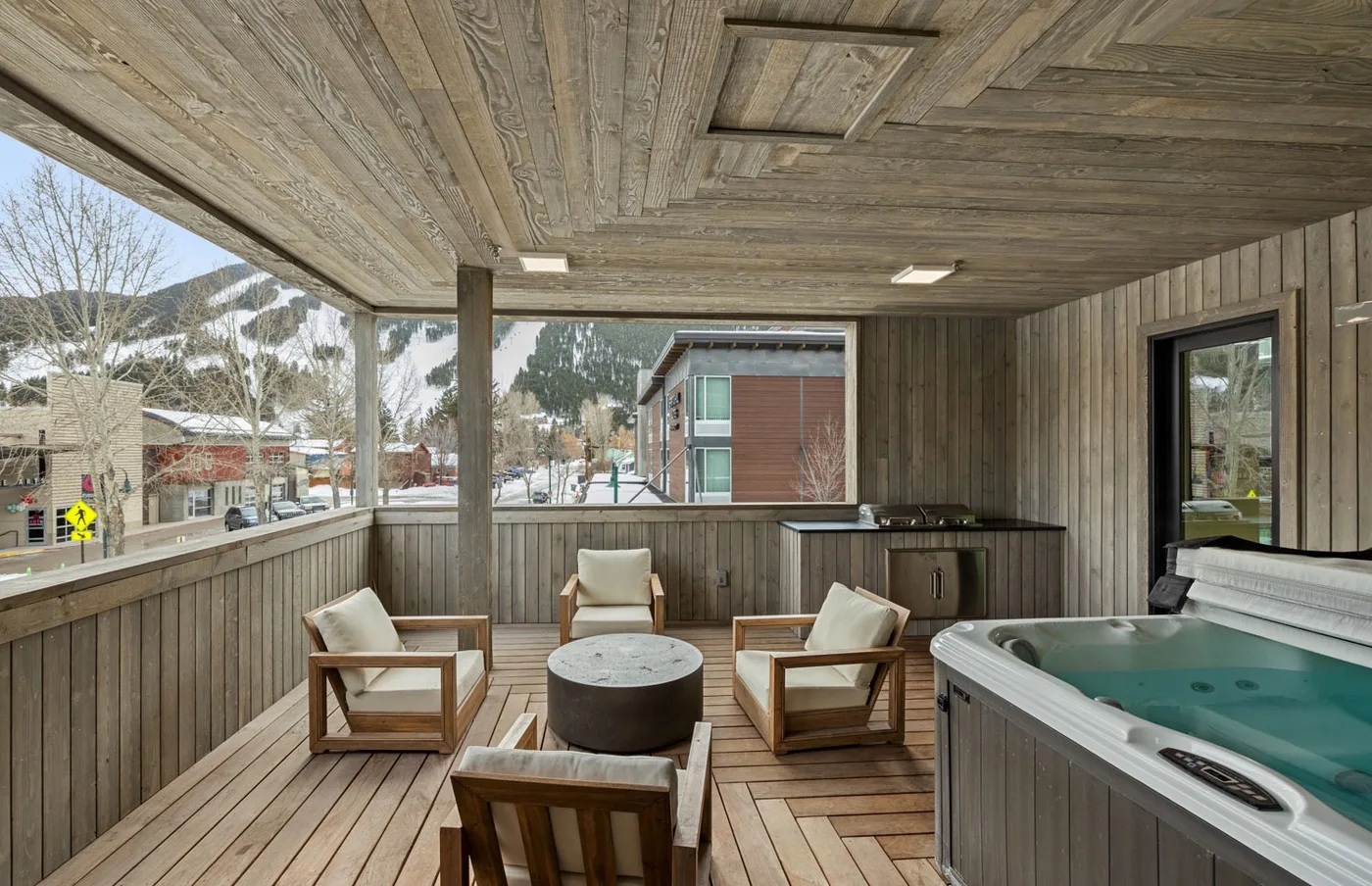 A covered outdoor seating area with a hot tub beside the windows.