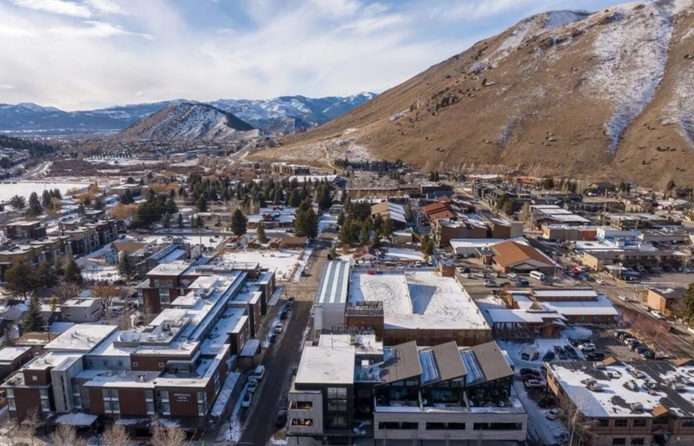 Aerial view of a snow-dusted mountain town beneath a broad hillside.