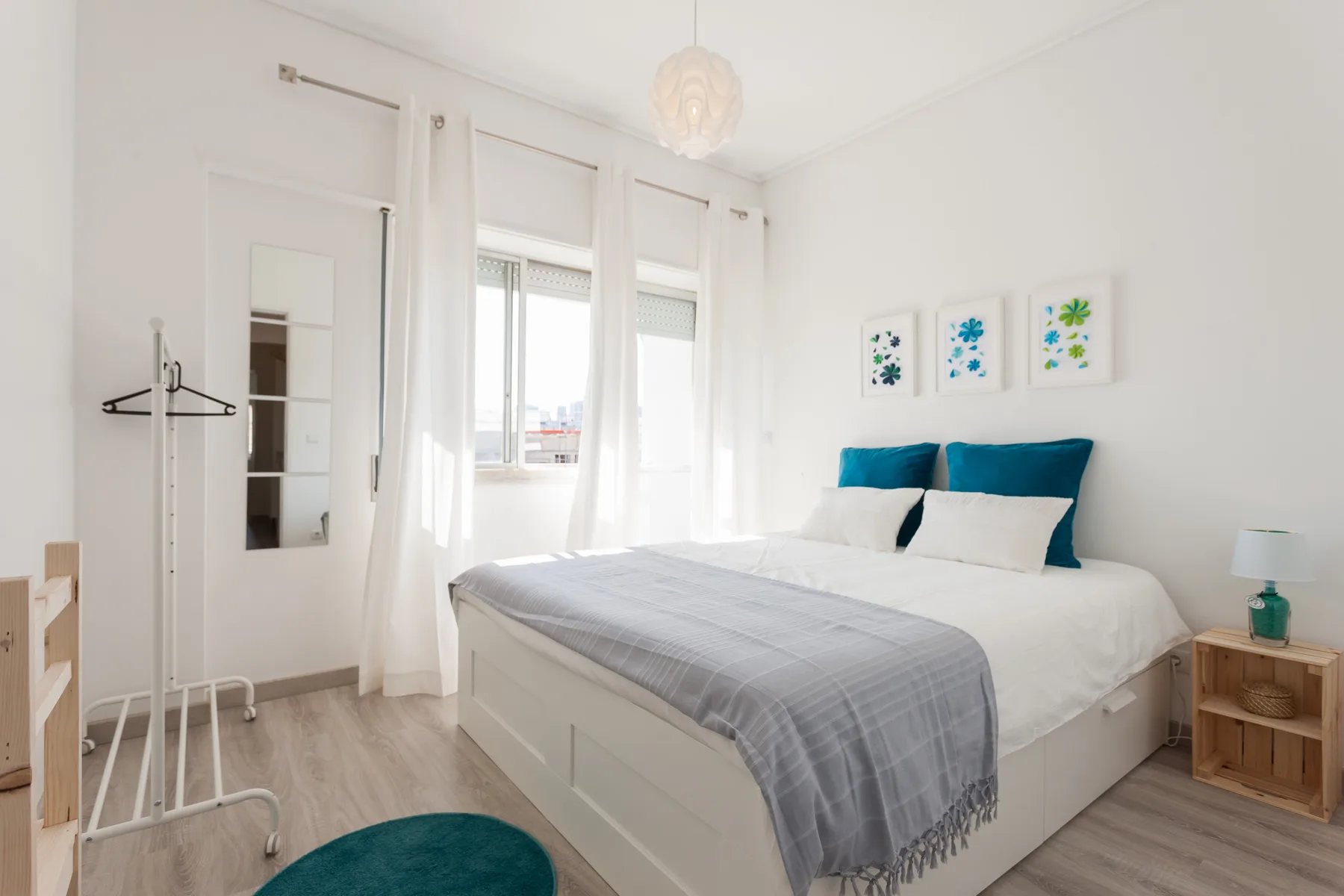 Un dormitorio luminoso con una cama tendida y ventanas altas.