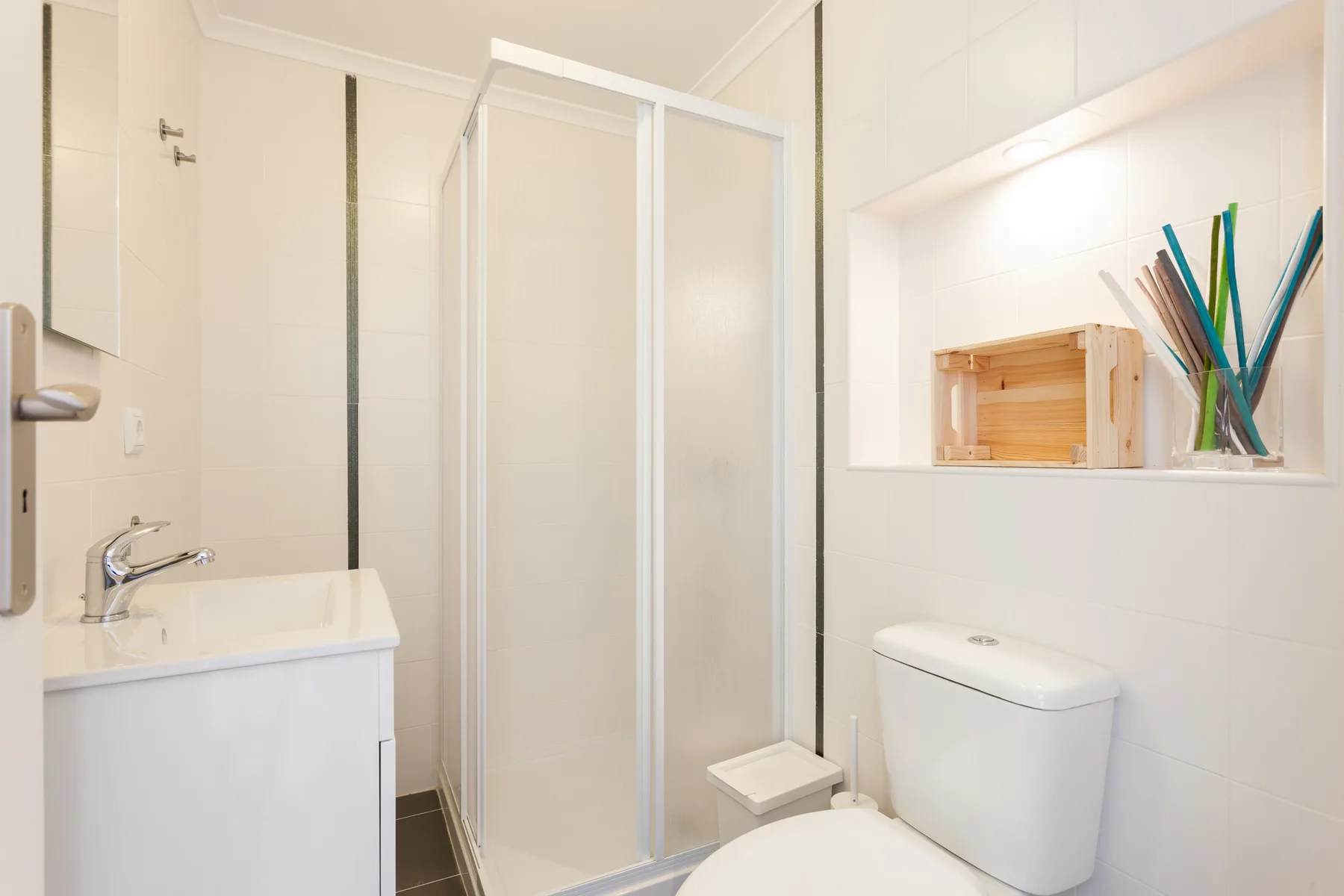 Un baño luminoso con ducha, lavabo e inodoro.