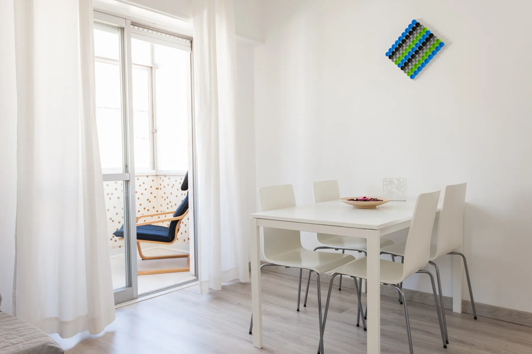 Comedor con una mesa blanca y sillas junto a una puerta de cristal.