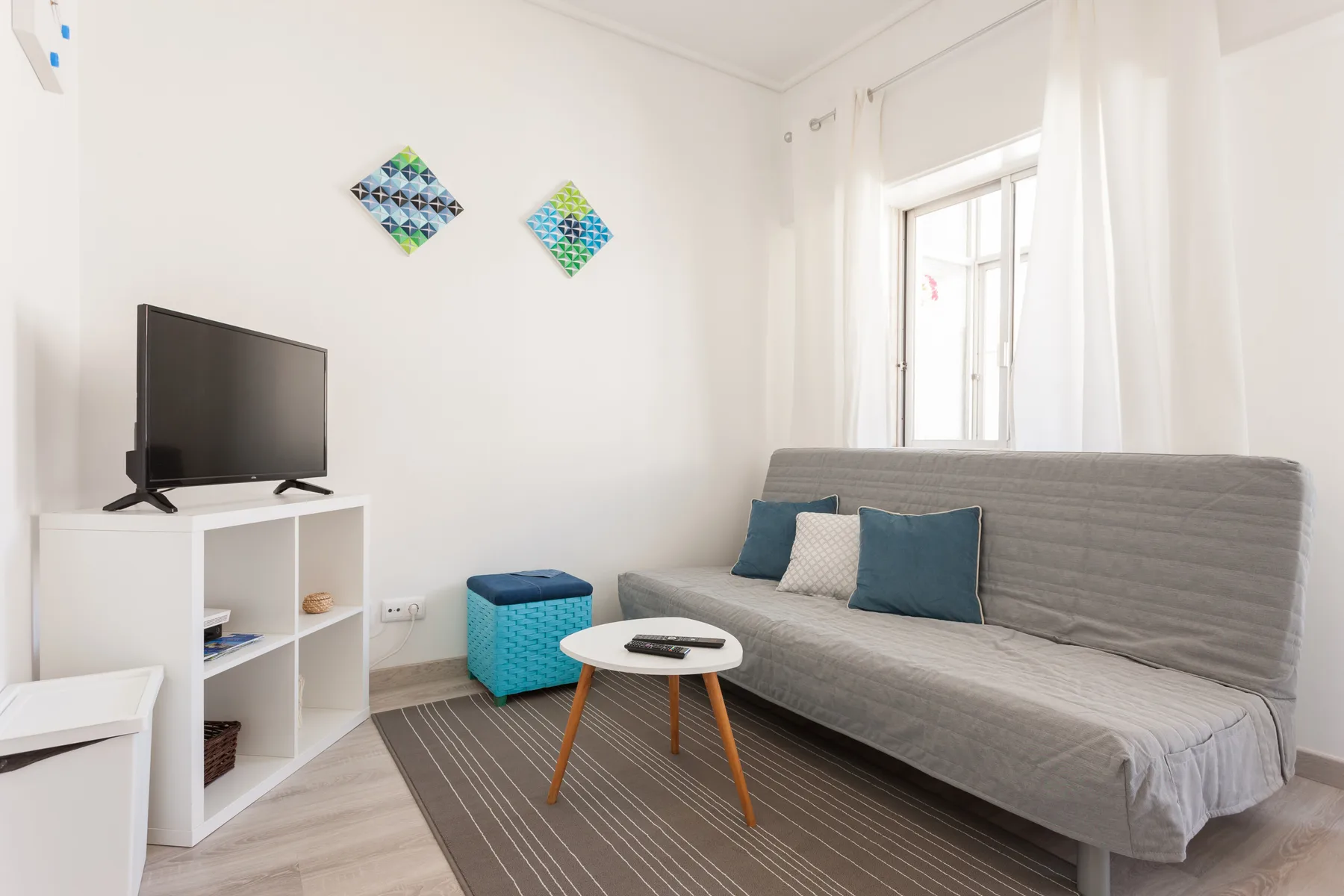Una sala luminosa con asientos, un televisor y una pequeña mesa de centro.
