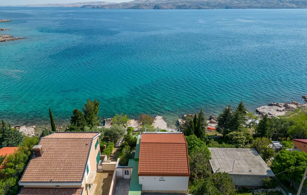 Aerial view of homes and trees beside a turquoise bay.