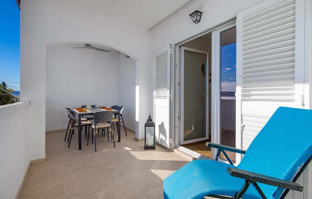 A sunlit patio with blue lounge seating and a dining table beneath an arched alcove.