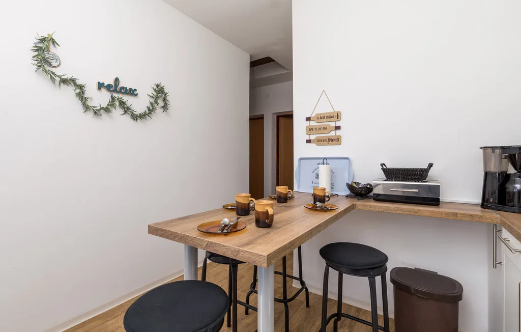 A small kitchenette has a wooden counter with stools and a coffee machine.