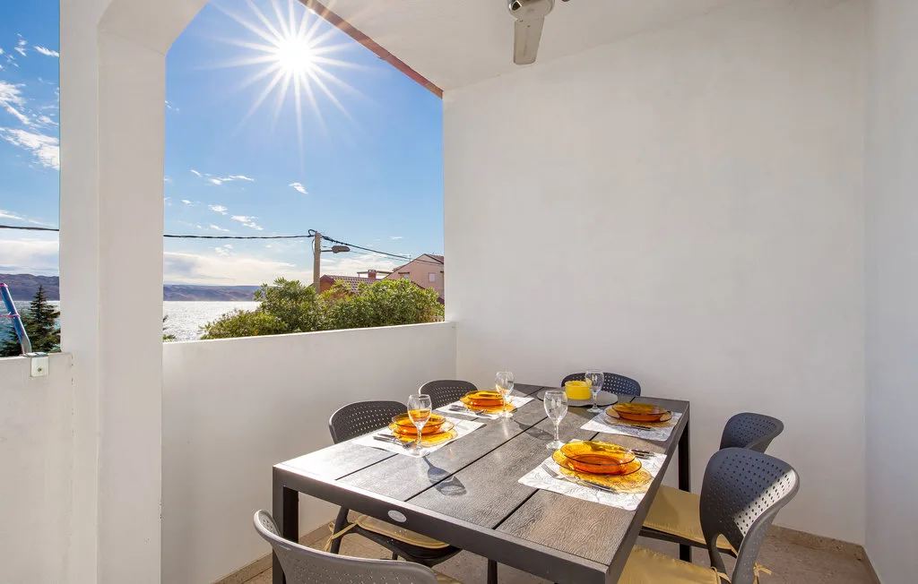 A covered outdoor dining area with a set table and a view of the sea.