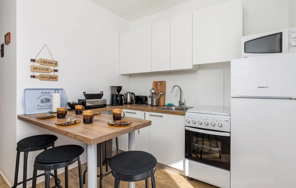 Una cocina luminosa con armarios blancos y una isla de madera.