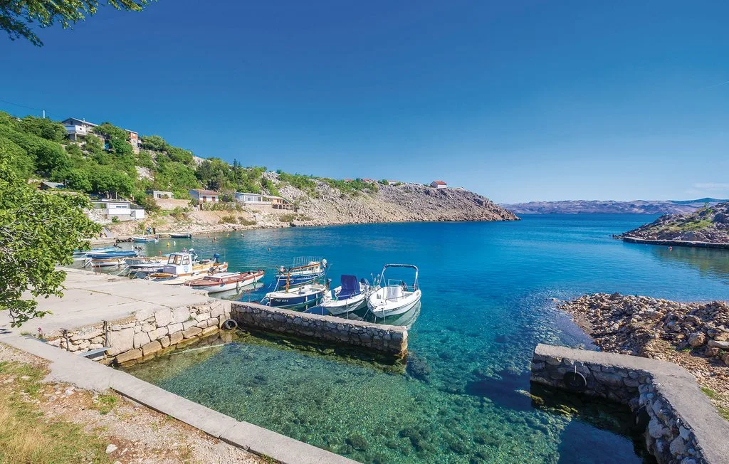 A seaside harbor with small boats moored in clear blue water.