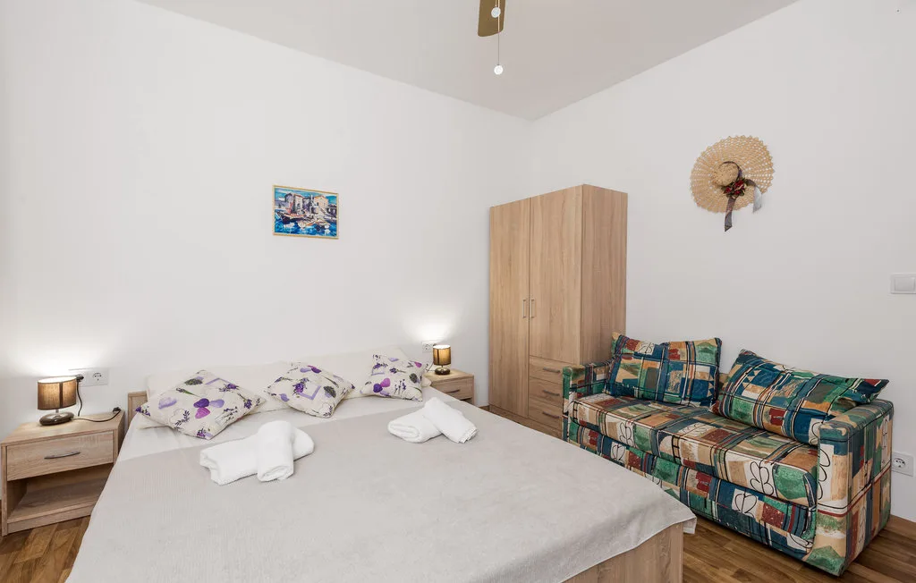 Un dormitorio con una cama, toallas dobladas, un armario y una zona de asientos estampados.