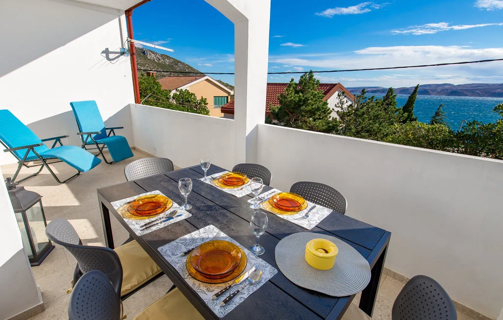 An outdoor dining area with a set table and a view of the sea.