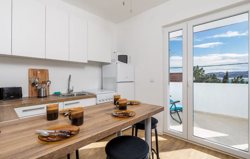 A bright kitchen and dining area opens onto a balcony with a water view.