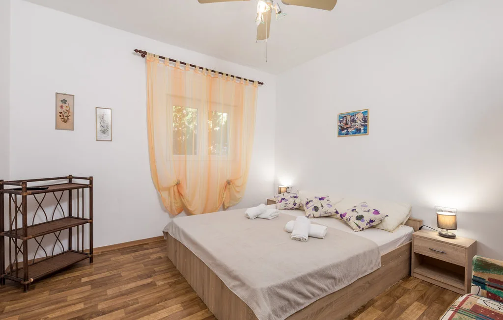 A bedroom with a neatly made bed beneath a curtained window.