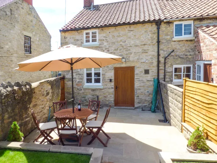 A stone courtyard with outdoor seating beneath a large patio umbrella.